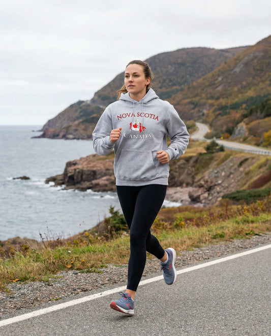 Person running on a road by the ocean wearing a 'Nova Scotia, Canada' hoodie.