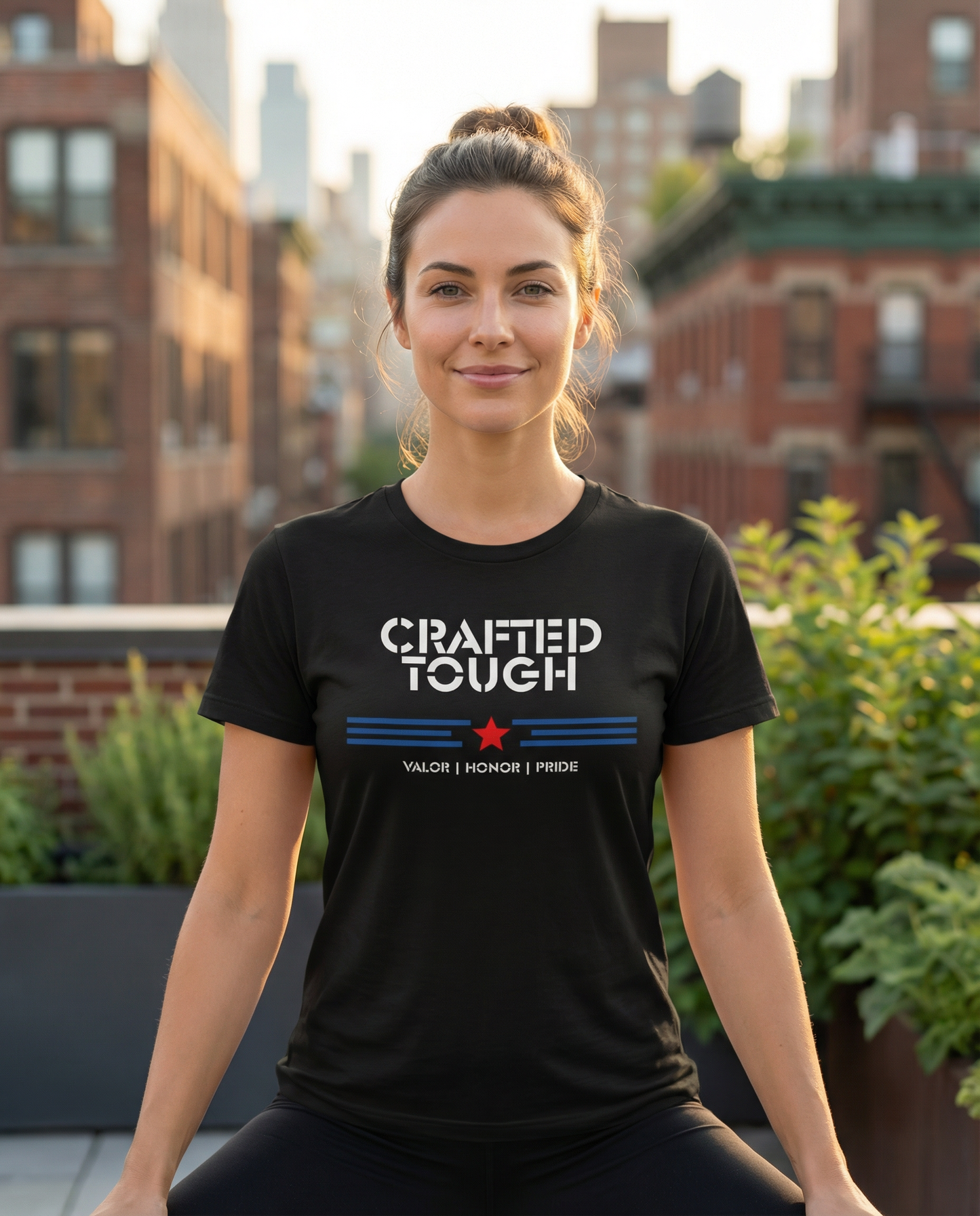 Woman wearing a black t-shirt with 'Crafted Tough' text on a rooftop with buildings in the background