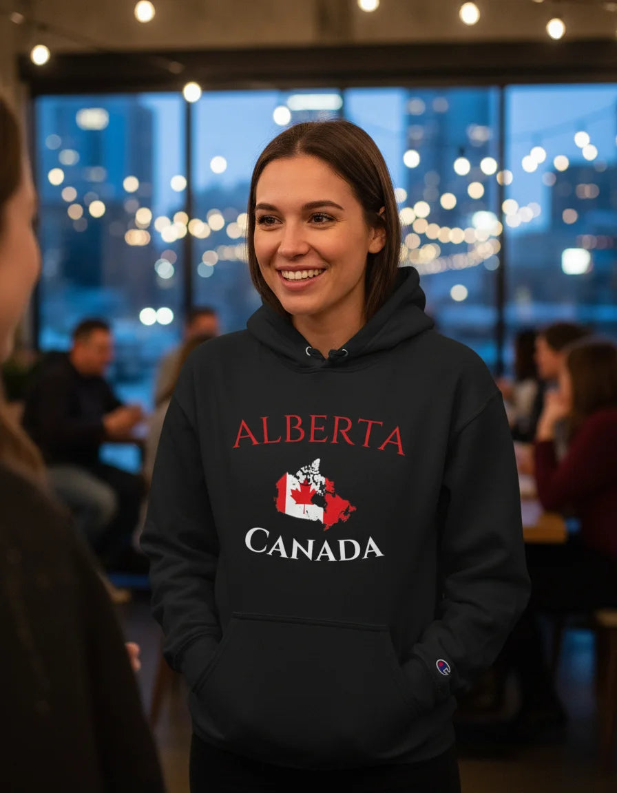 Person wearing a black hoodie with 'Alberta Canada' text and a maple leaf design, standing in a social setting.