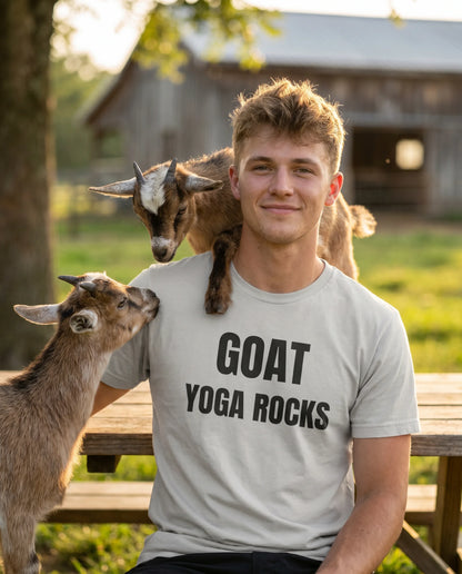 Man wearing a 'GOAT YOGA ROCKS' shirt with goats in a farm setting