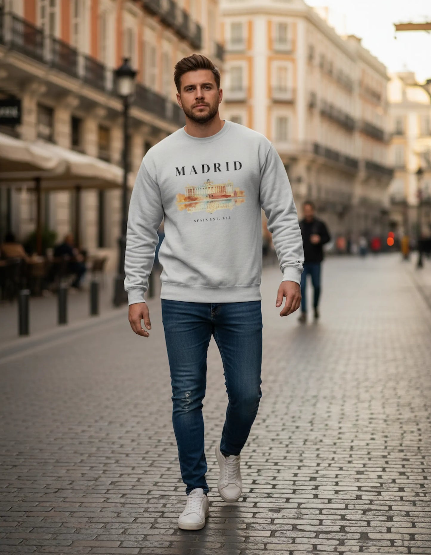 Man wearing a 'Madrid' sweatshirt walking on a city street.
