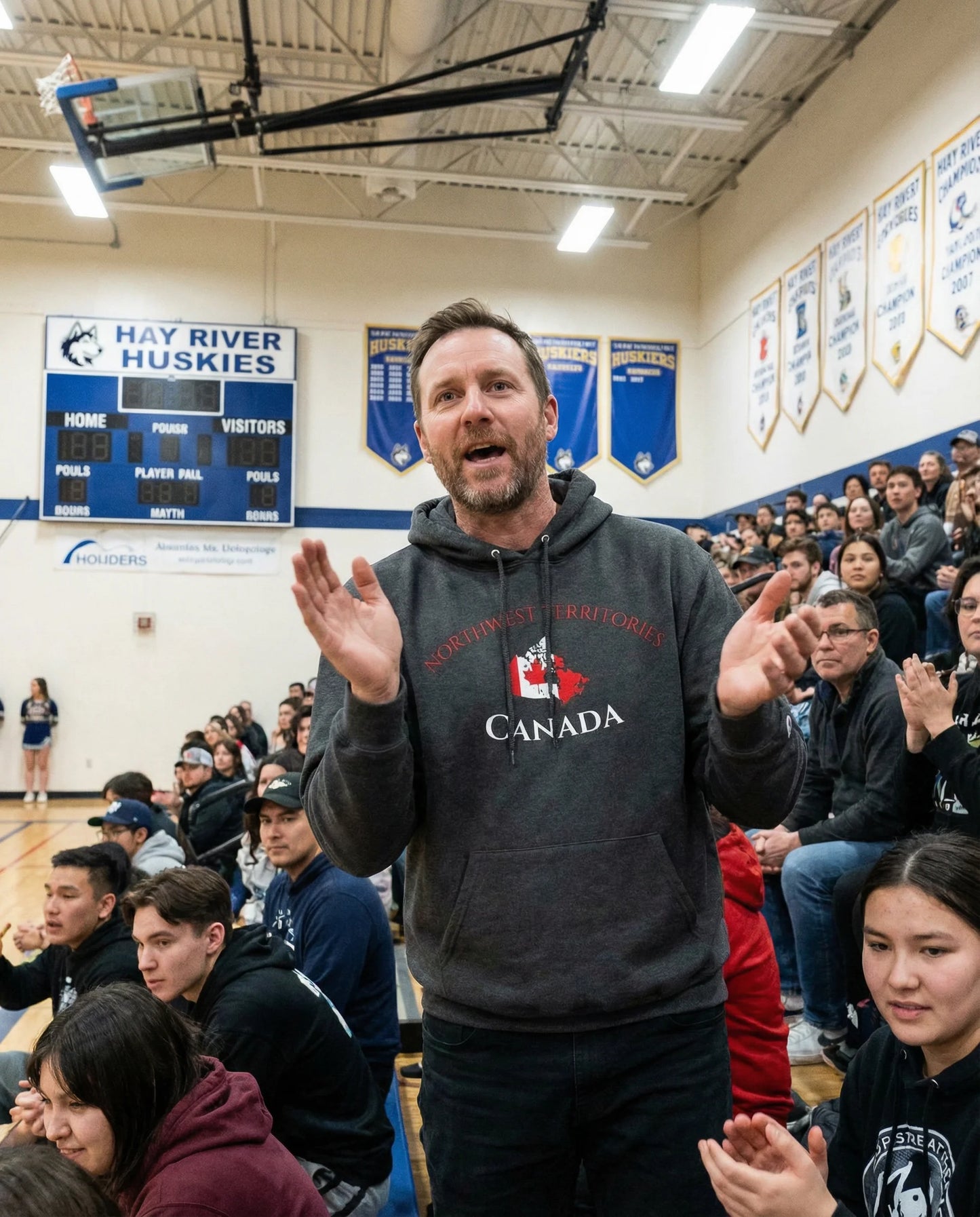 Man in a gray hoodie with 'Canada' text in a gymnasium with spectators.