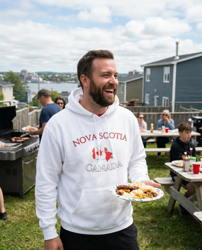 Man wearing a 'Nova Scotia, Canada' hoodie holding a plate of food outdoors.