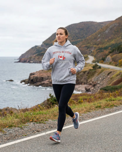 Person running on a road by the ocean wearing a 'Nova Scotia, Canada' hoodie.