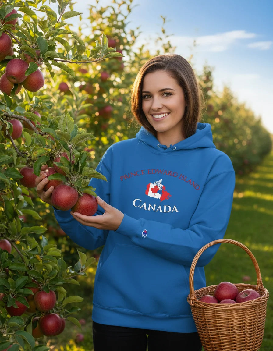 Woman in a blue hoodie with 'Canada' text holding apples in an orchard