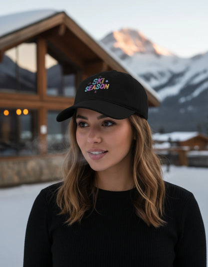 Woman wearing a black cap with 'Ski Season' text in a snowy mountain setting