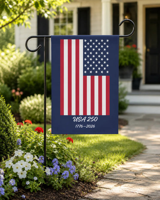 American flag garden flag with 'USA 250' text in a garden setting.