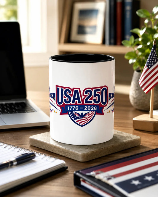 White mug with 'USA 250' design on a desk with laptop and stationery