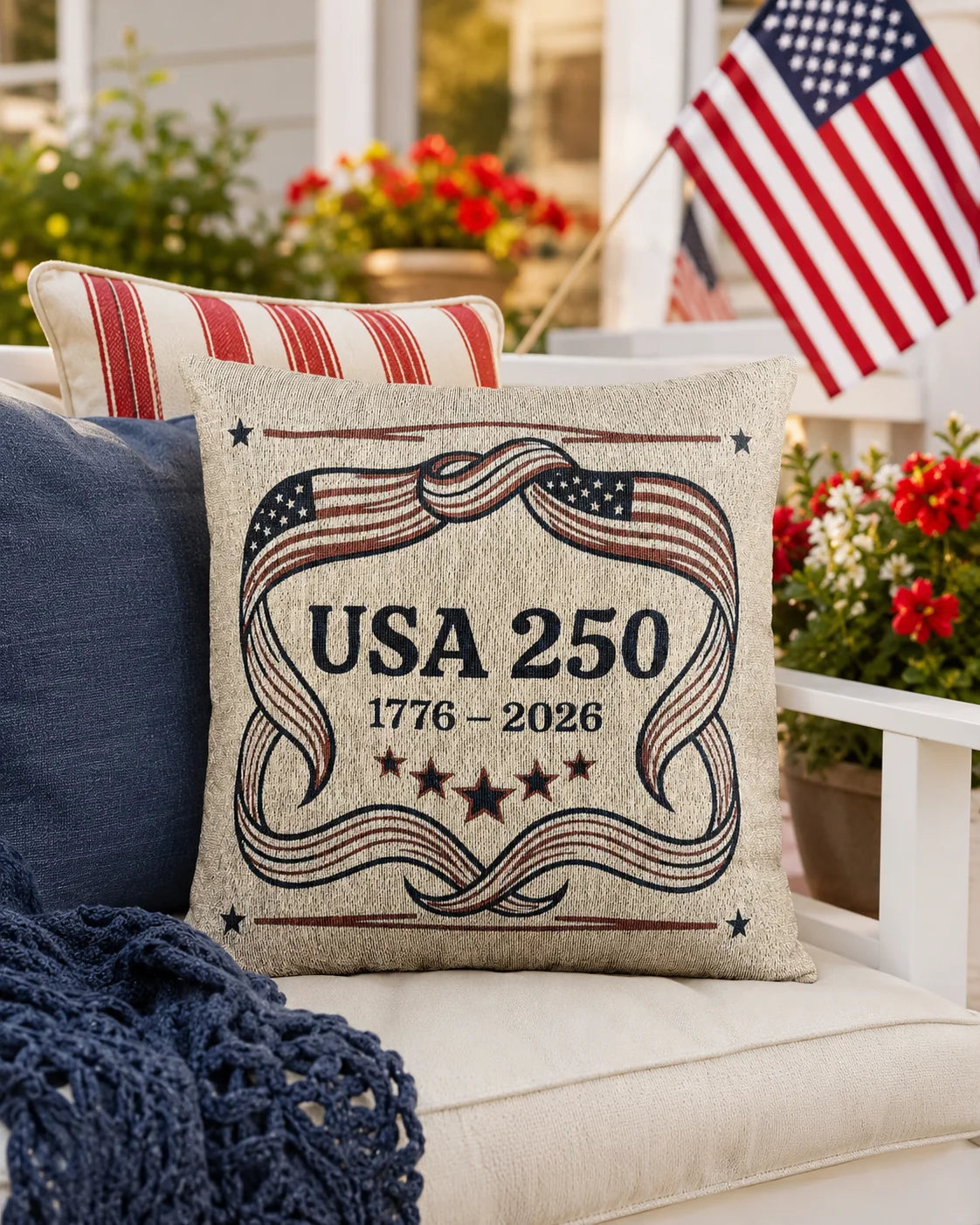 Decorative pillow with 'USA 250' design on a couch outdoors with American flag and flowers in the background.
