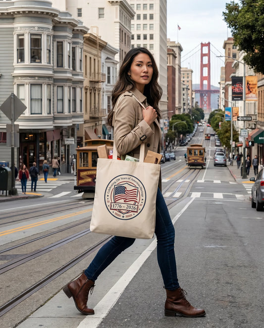 Woman holding a tote bag with a logo on a city street with the Golden Gate Bridge in the background.